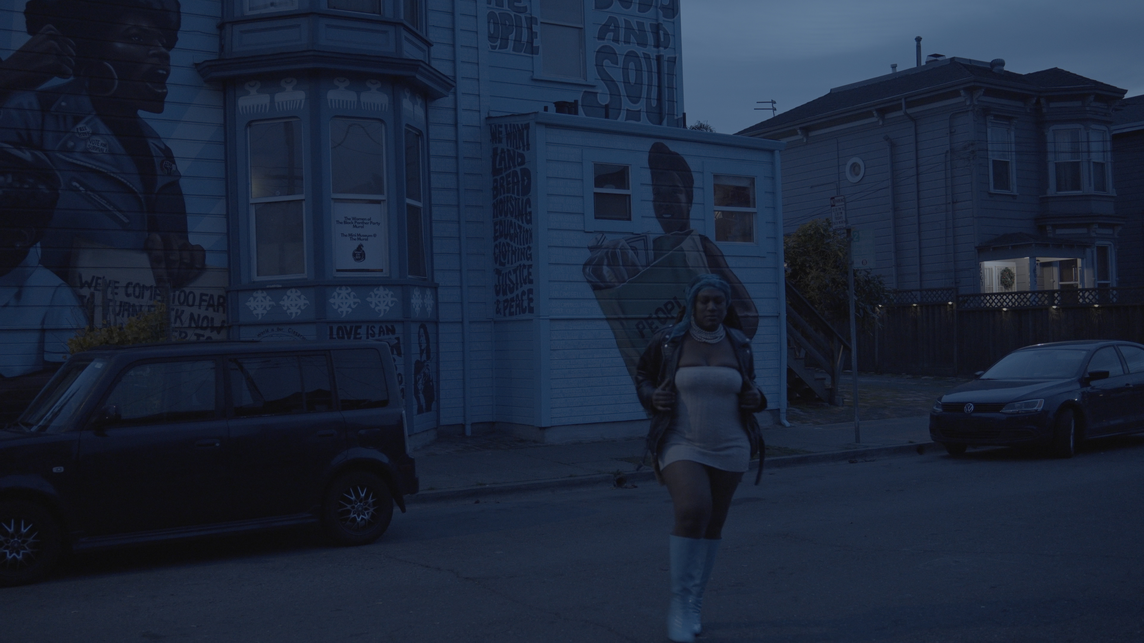 Nikkita walking past Oakland murals